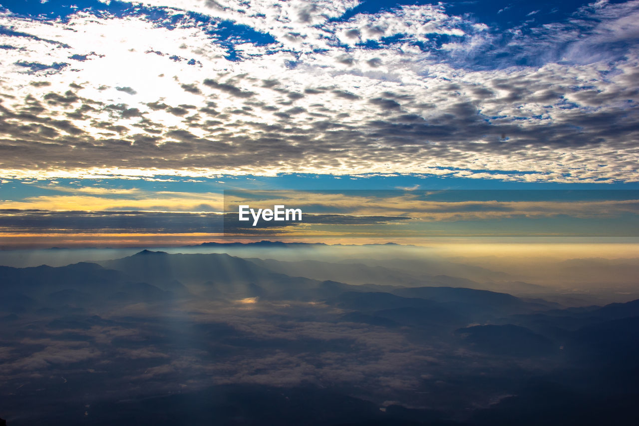 AERIAL VIEW OF CLOUDS OVER MOUNTAINS DURING SUNSET