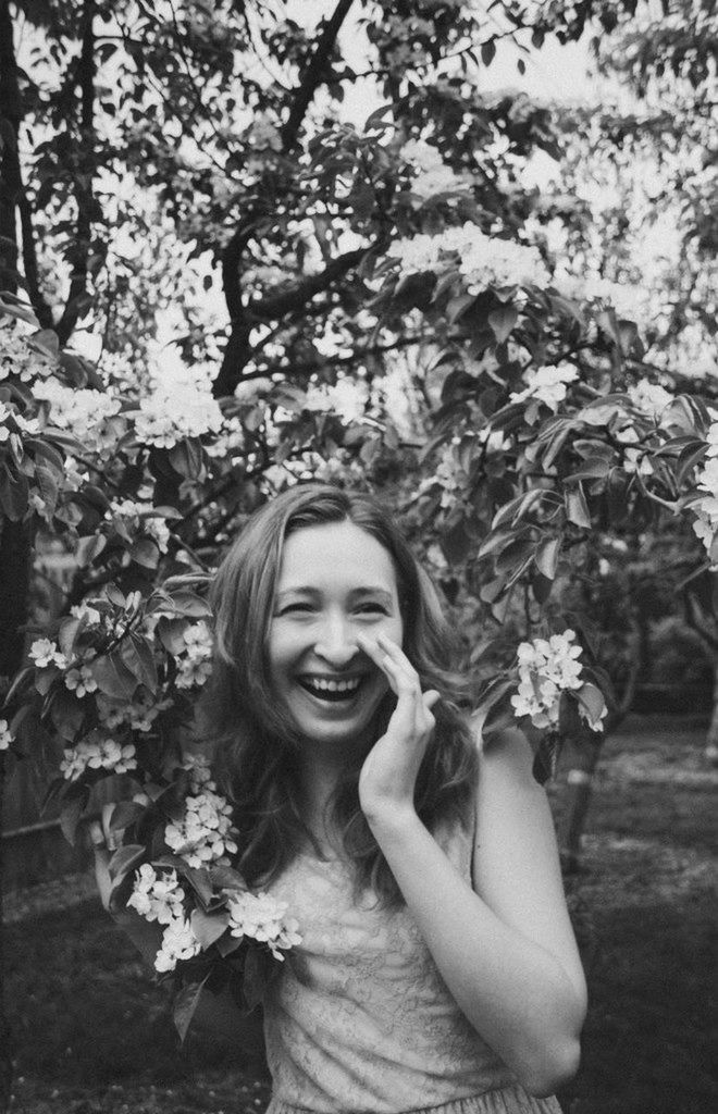 Portrait of a cheerful young woman against flower tree