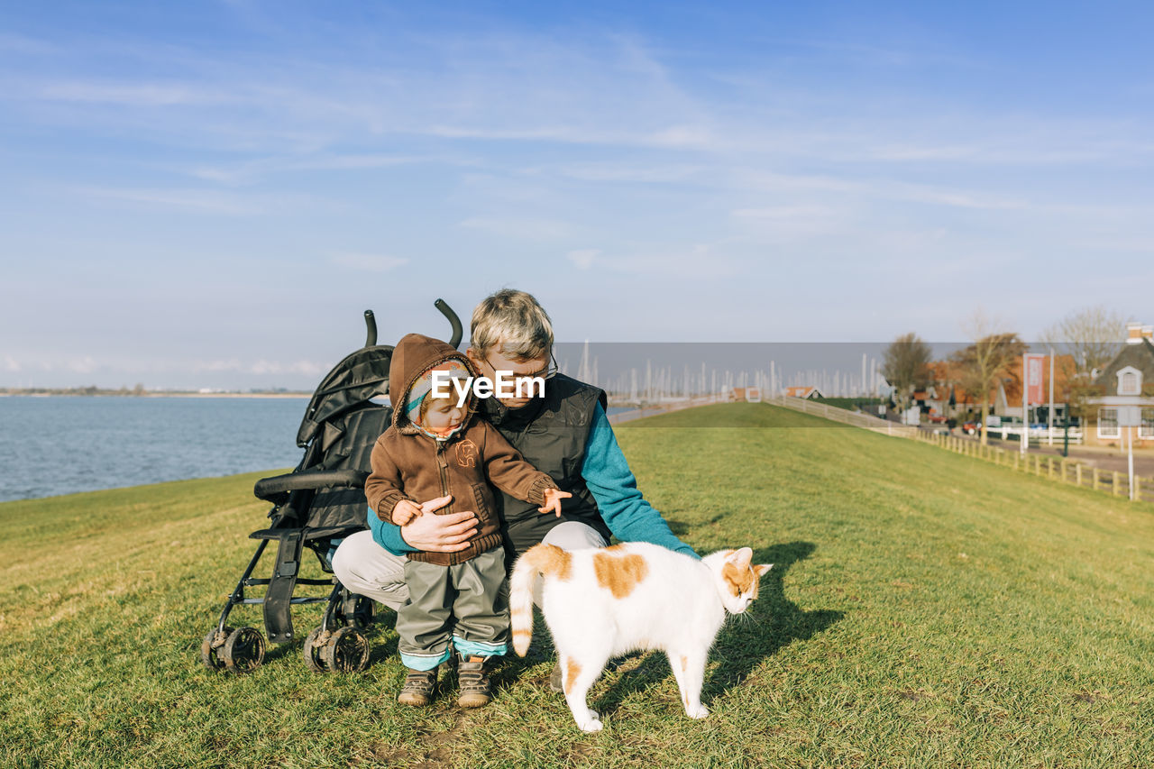 Senior man with granddaughter and cat on land during sunny day