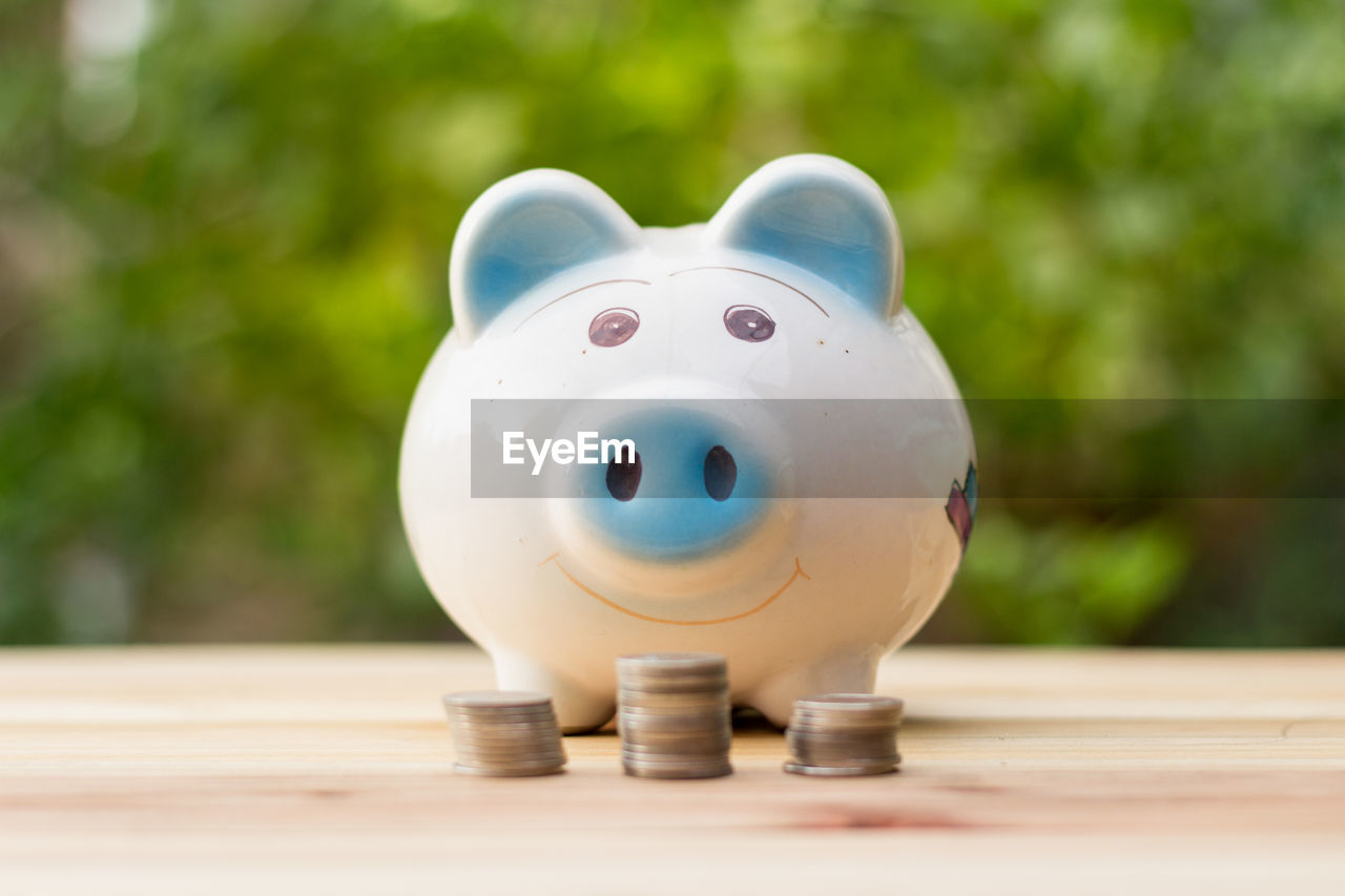 Close up of piggy bank with coins on wooden table