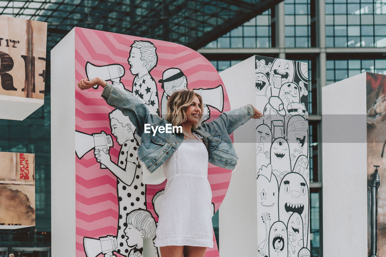 WOMAN STANDING BY GRAFFITI WALL