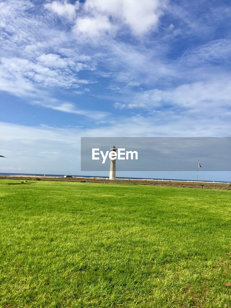 Lighthouse on field against sky