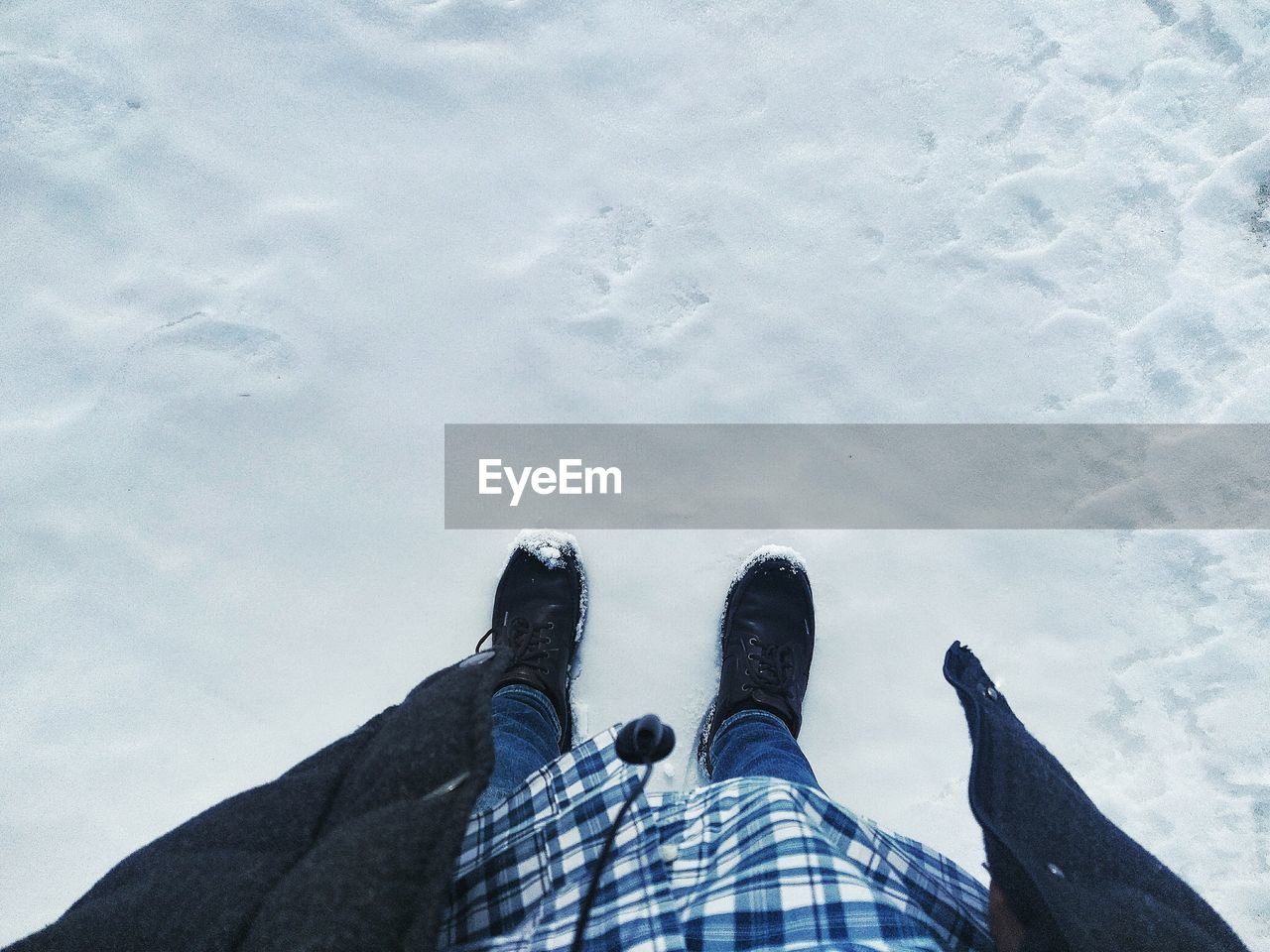 Low section of man standing on snow covered field during winter