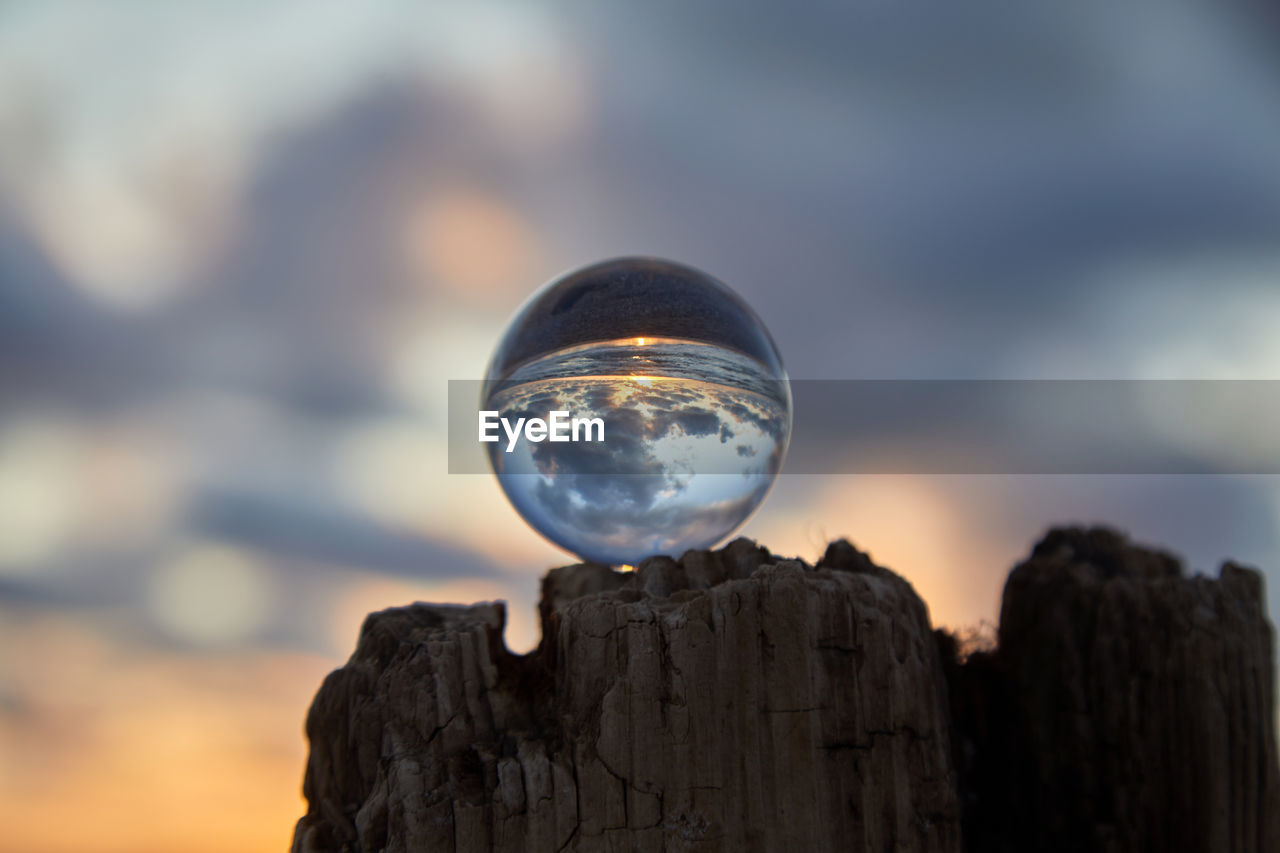 CLOSE-UP OF CRYSTAL BALL AGAINST WOODEN POST