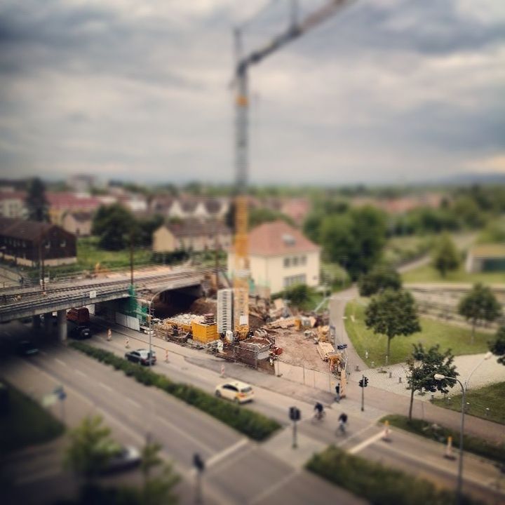 Tilt-shift image of cars on street against cloudy sky