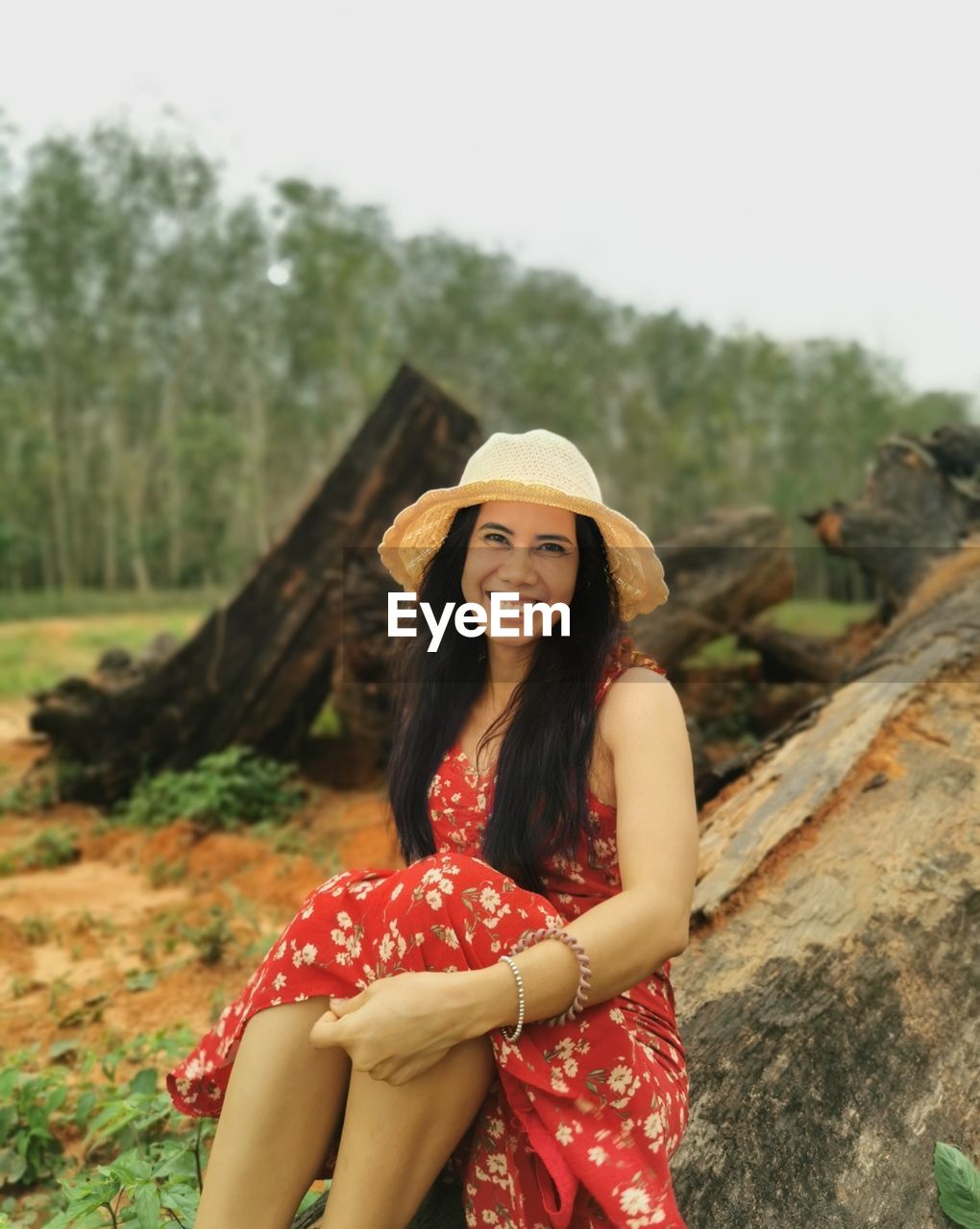 portrait of young woman sitting on rock against mountain