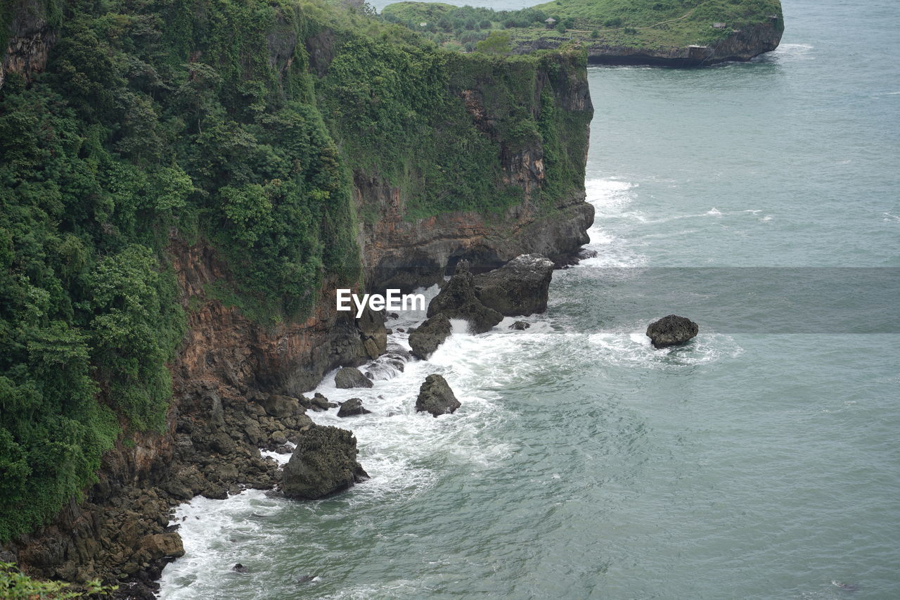 water, sea, beauty in nature, scenics - nature, land, rock, cliff, body of water, coast, nature, plant, beach, no people, tranquility, day, rock formation, non-urban scene, tranquil scene, shore, bay, tree, high angle view, outdoors, motion, terrain, coastline, idyllic, environment, mountain, cove, water sports, sports, green, travel destinations, wave, travel