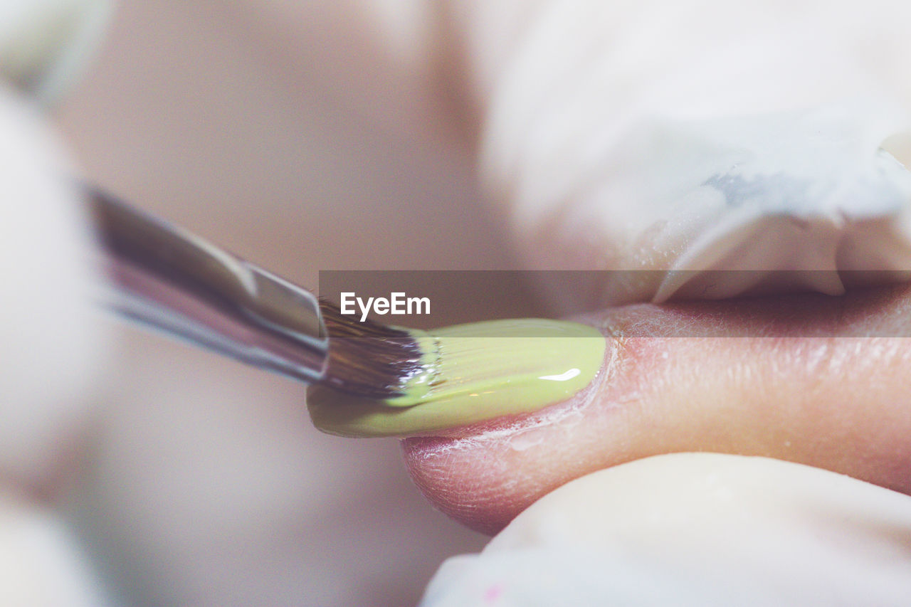 Cropped hand of beautician applying nail polish to woman