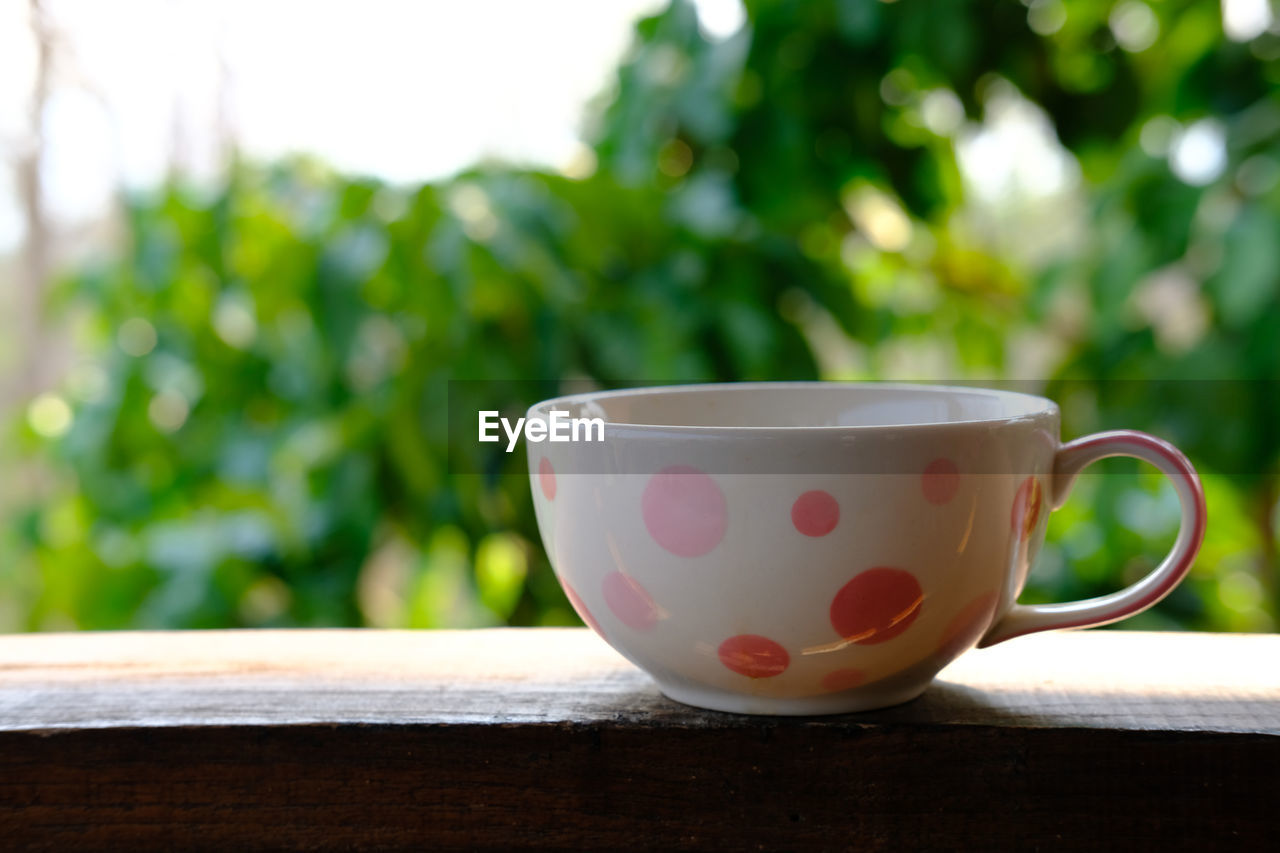 CLOSE-UP OF COFFEE CUP ON TABLE AGAINST BLURRED BACKGROUND