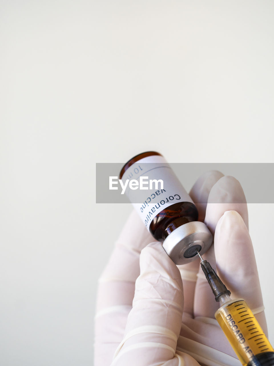 Doctor's hand holding a syringe of covid-19 vaccine and vaccine vial