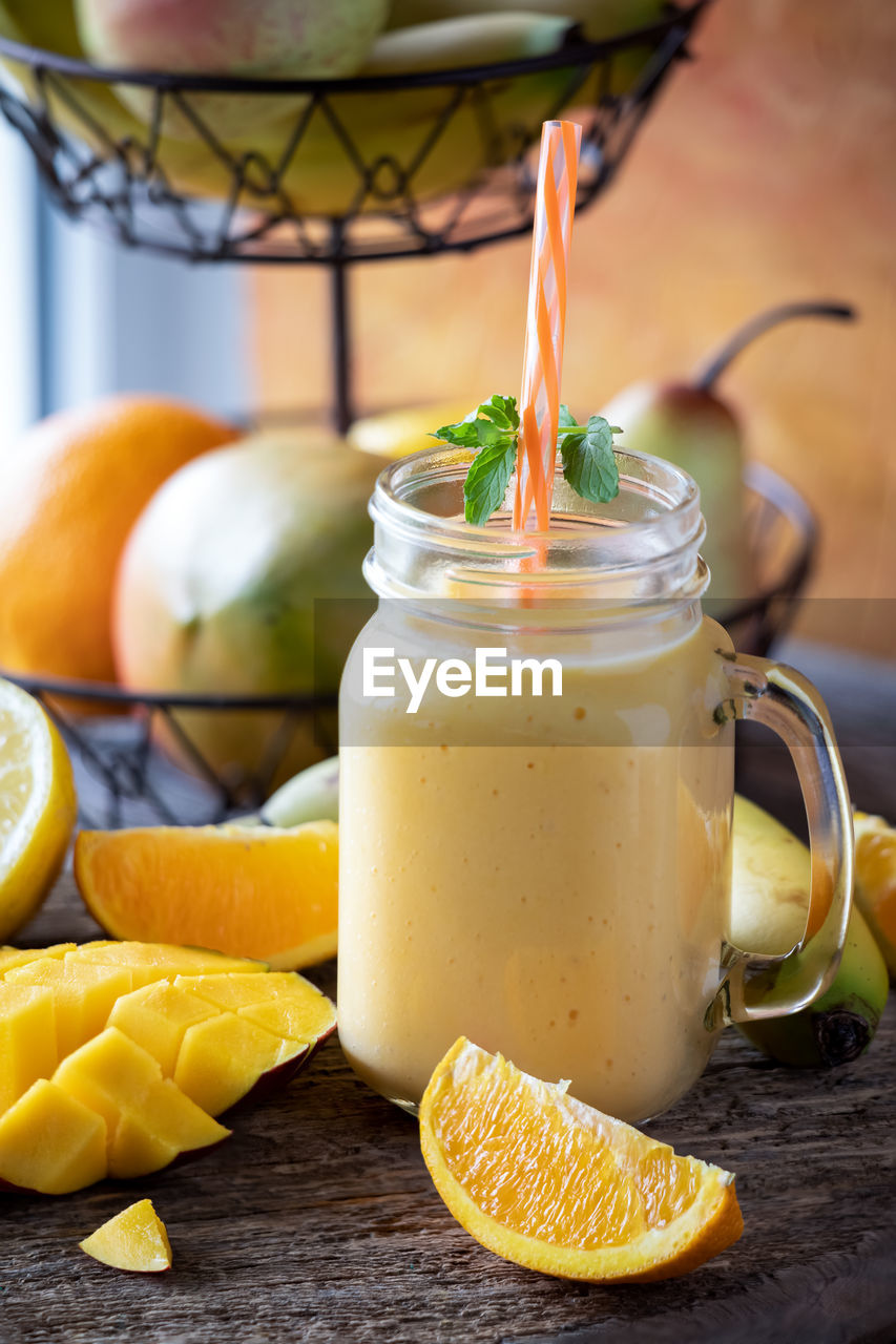 A jar mug filled with a refreshing healthy mango citrus smoothie.