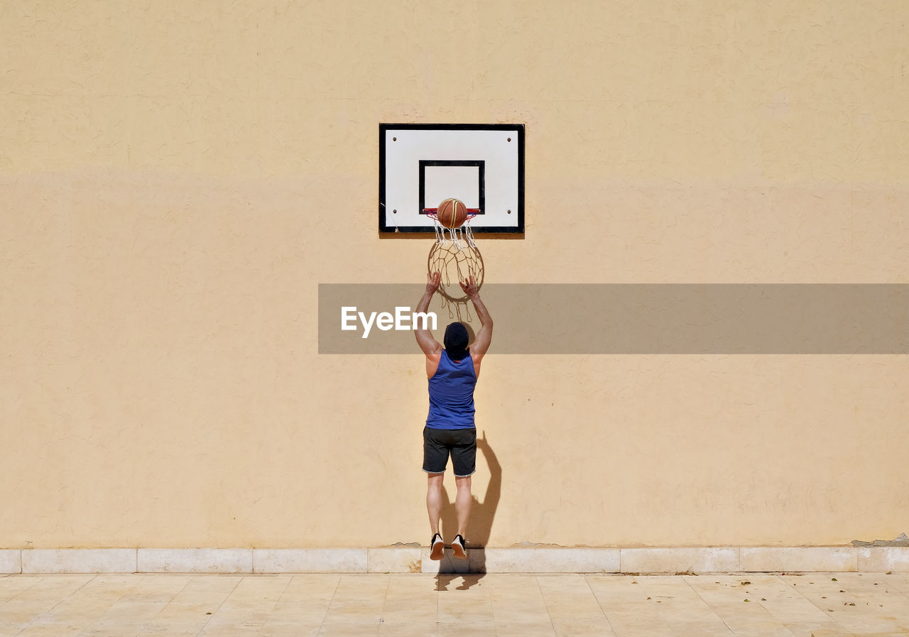 Full length of man jumping at basketball hoop