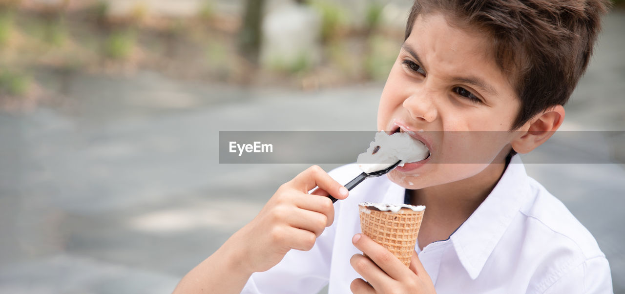 Cute child boy with a dirty face eats ice cream, the child enjoys dessert