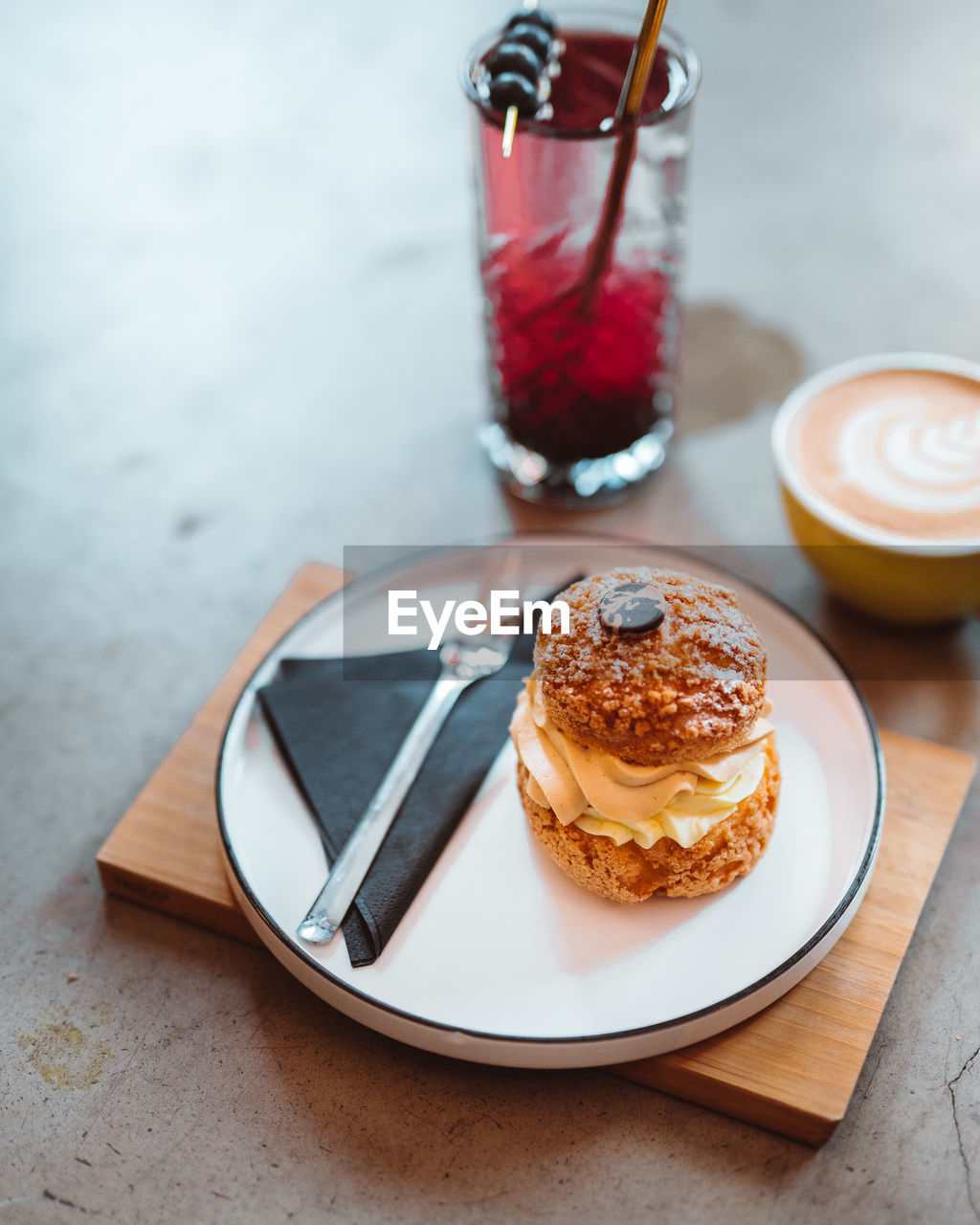 Cropped of the purple cocktail in glass, cake dessert and cappuccino standing on the table