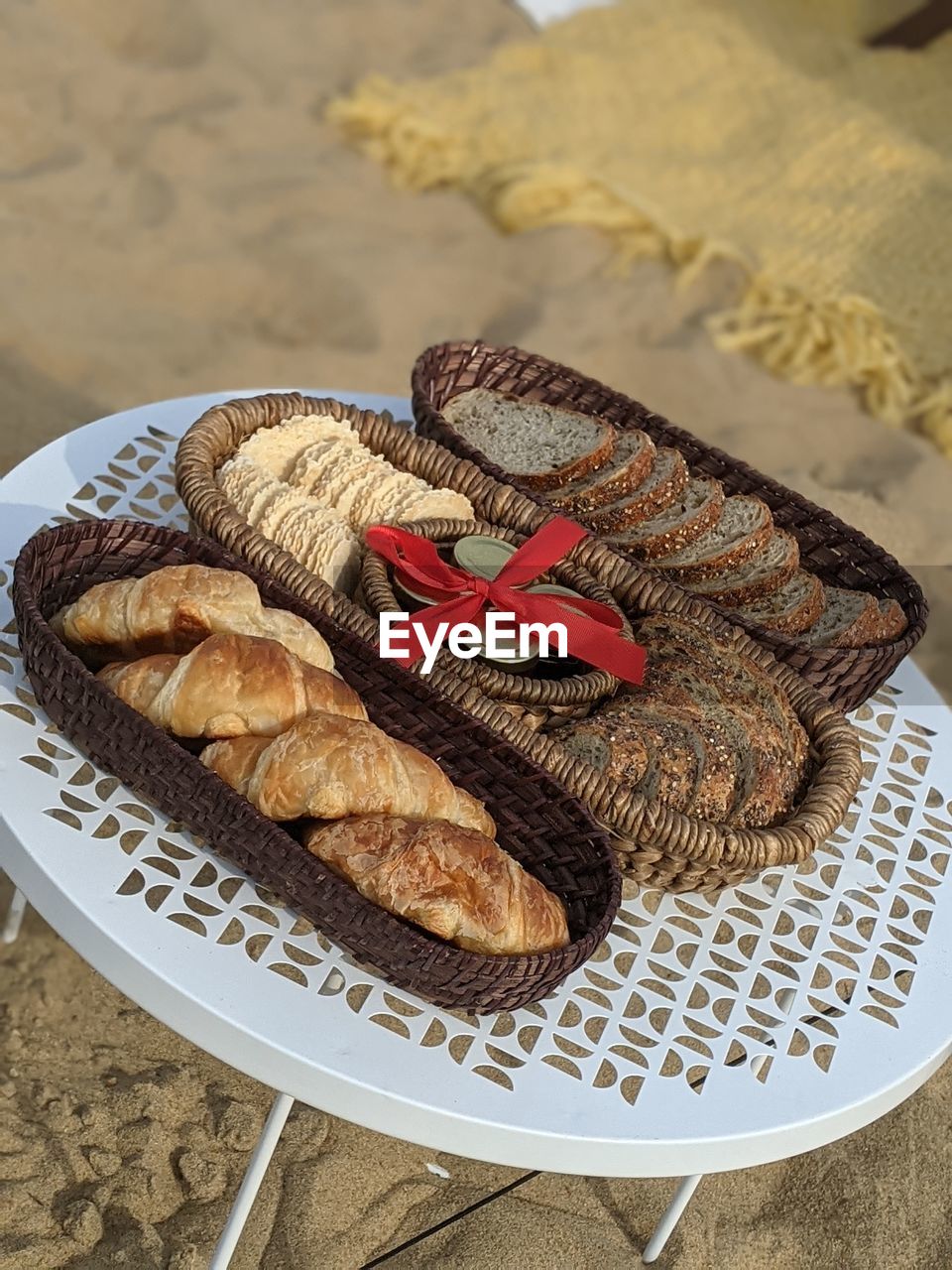 A bread picnic baskets with preserves neatly tied by a red bow in the middle.