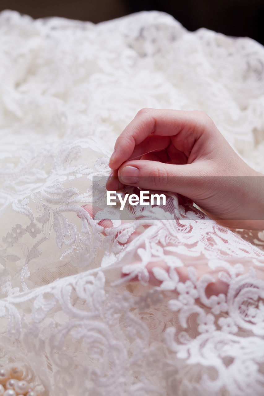 Cropped hands of woman stitching wedding dress