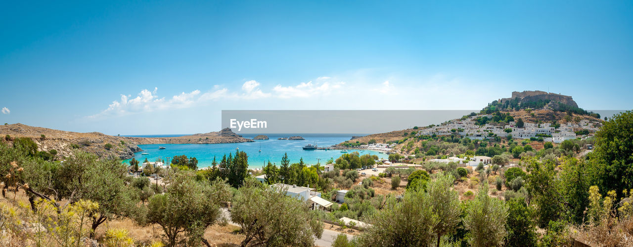 Panoramic view of sea and mountains against blue sky