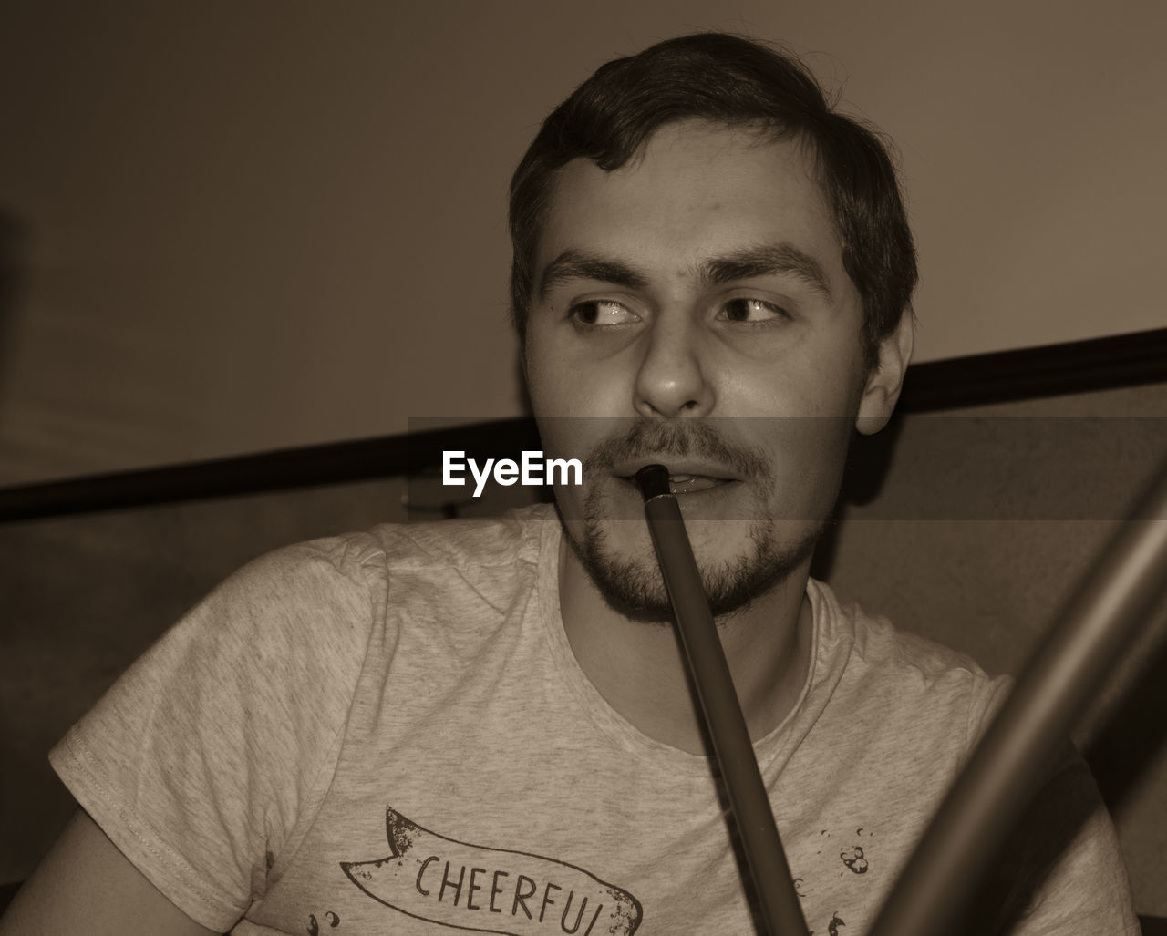 PORTRAIT OF YOUNG MAN HOLDING EYEGLASSES