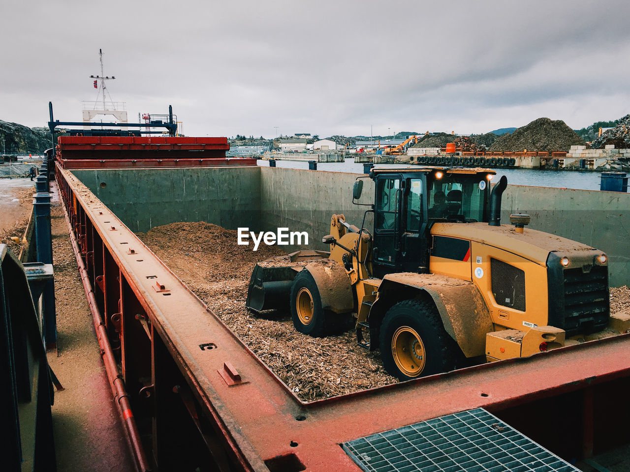 Earth mover in barge against sky