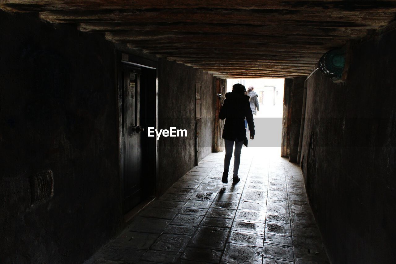 Rear view of woman walking in tunnel