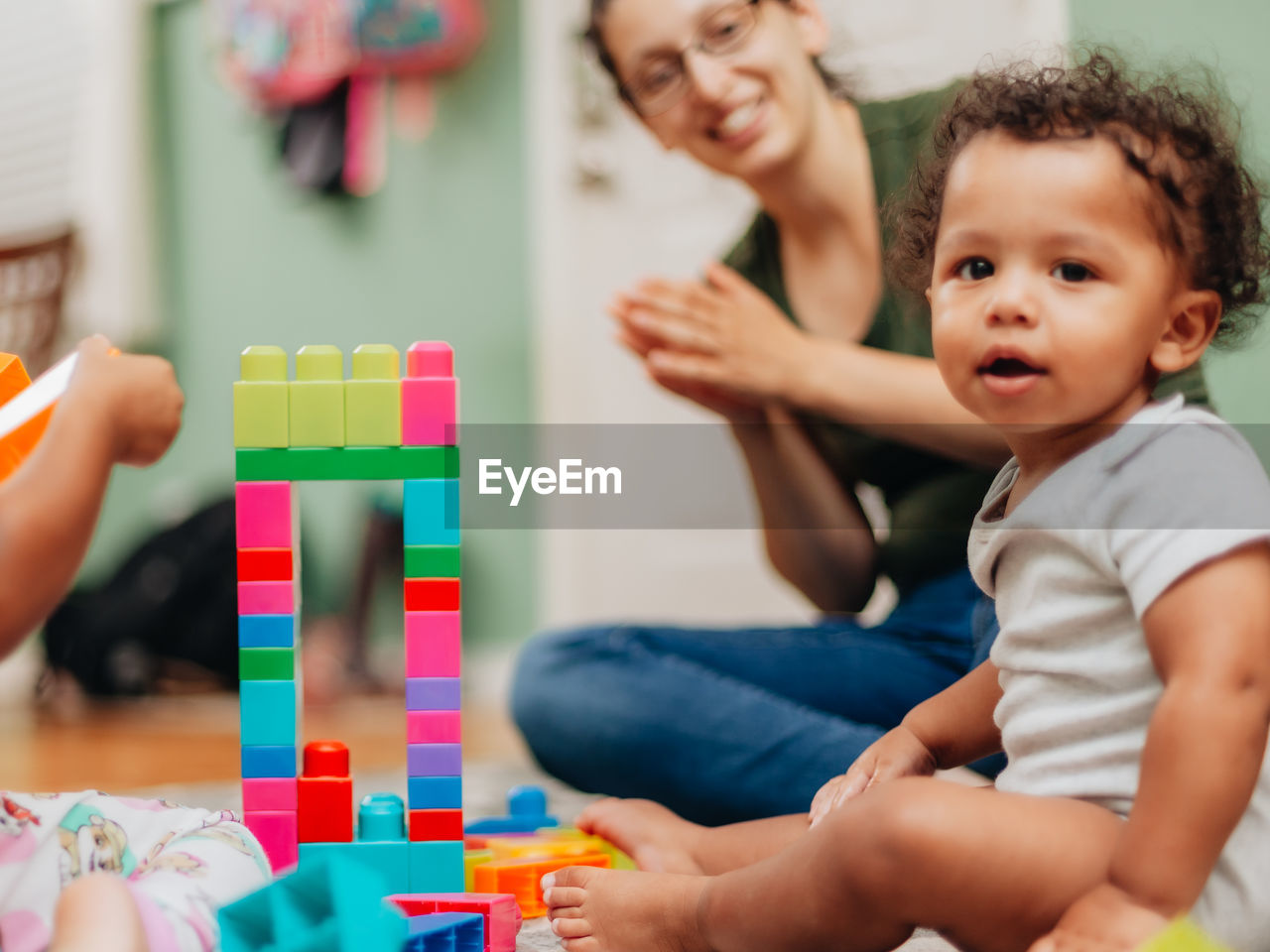 Cute boy playing with toy sitting with mother at home