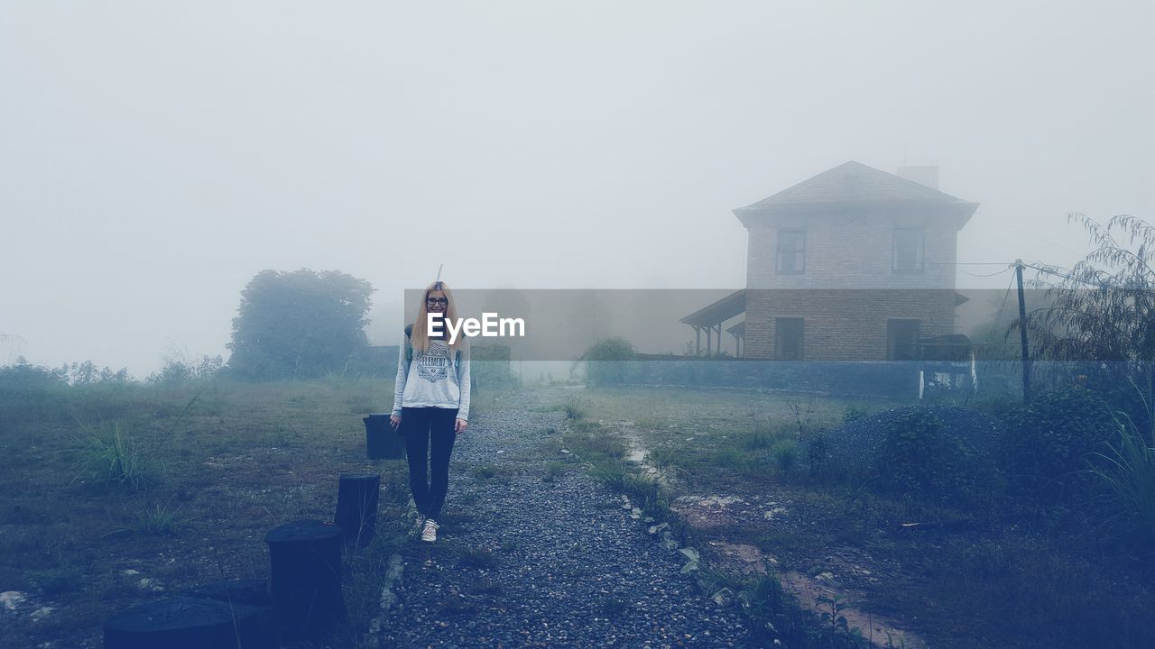 Young woman walking on footpath during foggy weather