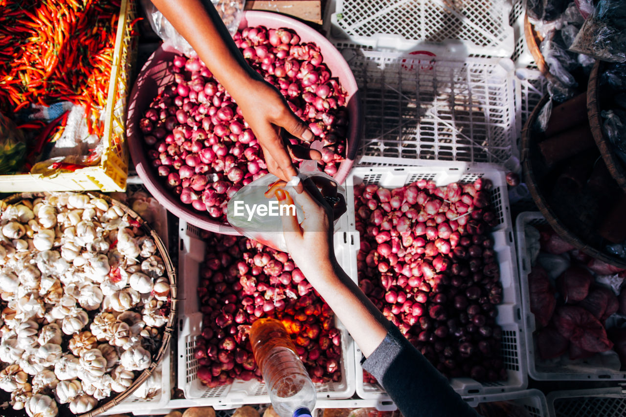 Cropped hands of people shopping vegetables at market stall