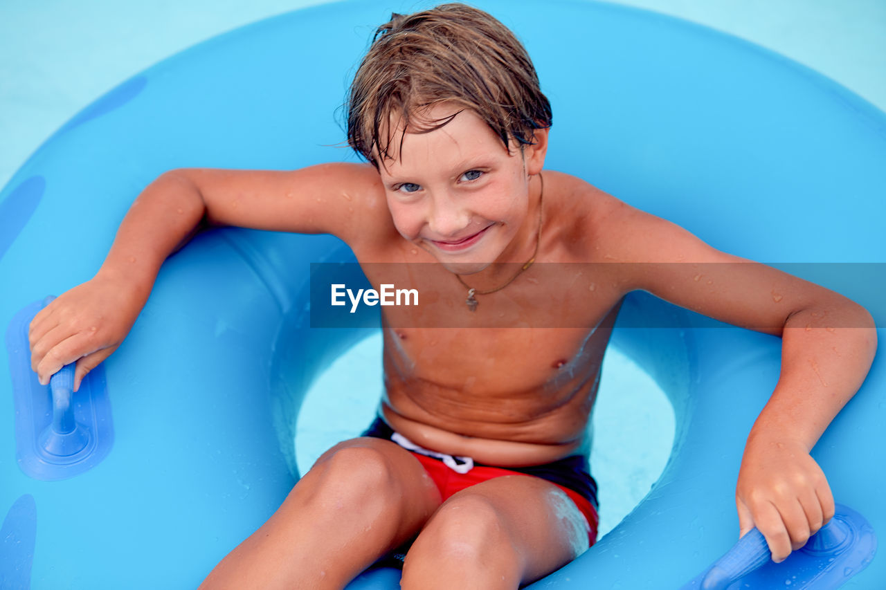 Portrait of boy sitting on inflatable ring