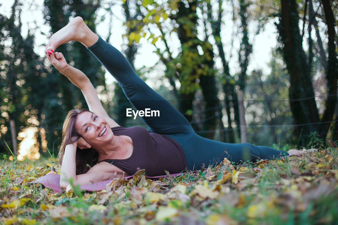 Woman exercising while lying down by tree at park