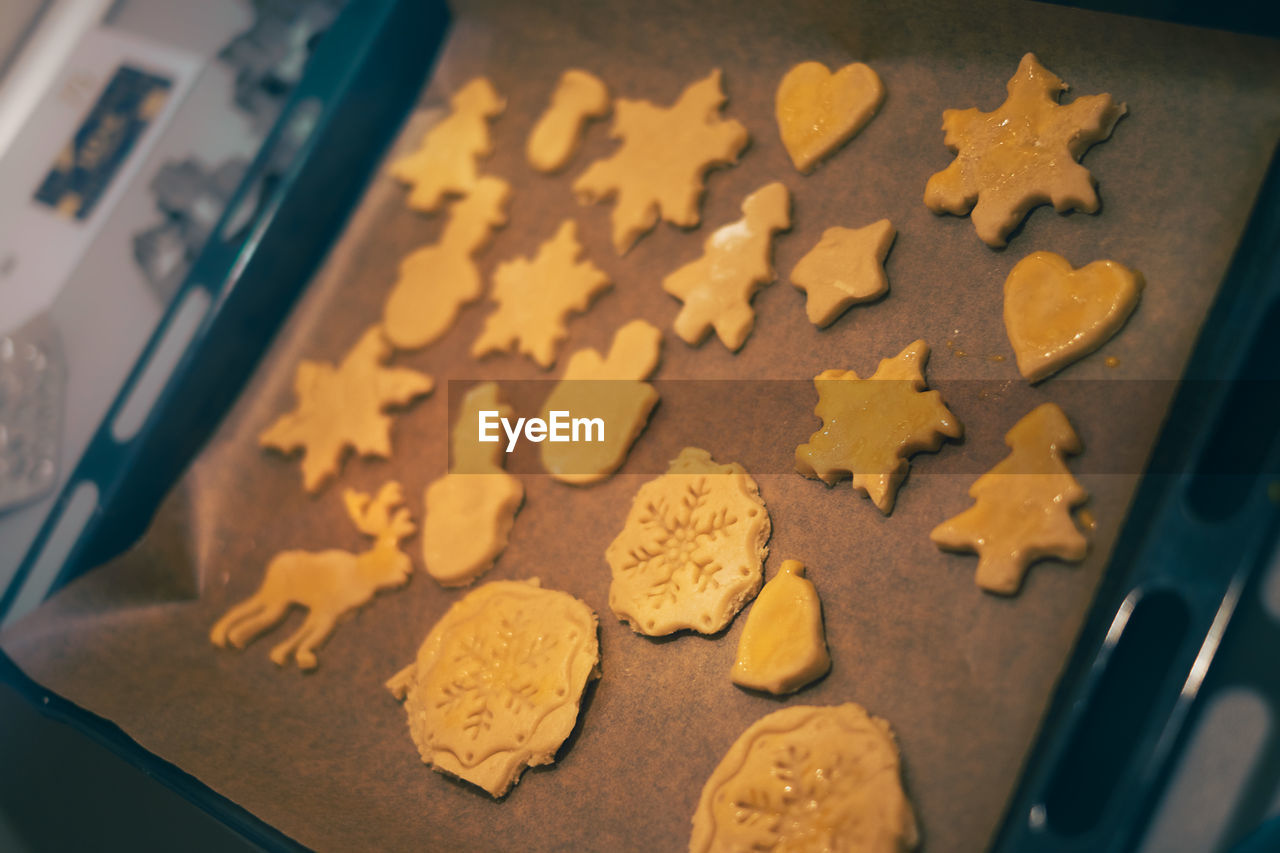 Baking sheet with christmas cookies in the shapes of deers, snowflakes, hearts, snowmen, bells.