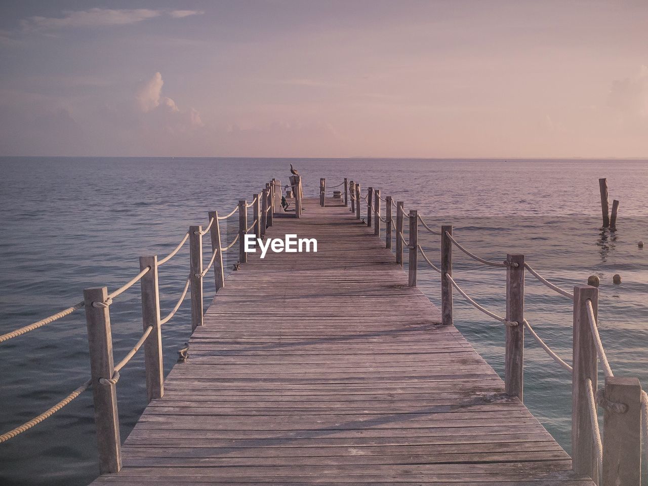 Jetty over sea against sky during sunset