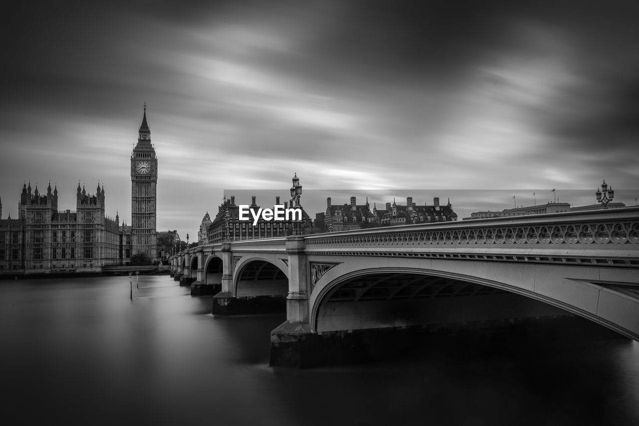 Arch bridge over river against sky in city