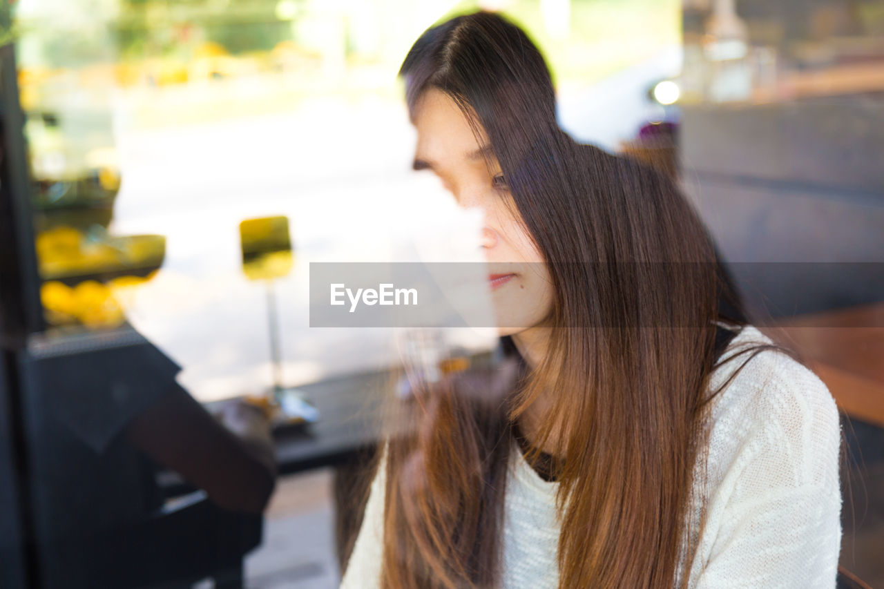 Woman sitting in restaurant seen through window