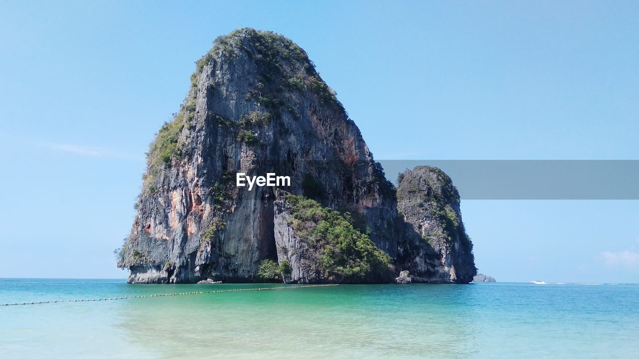 View of rock formation in sea against blue sky