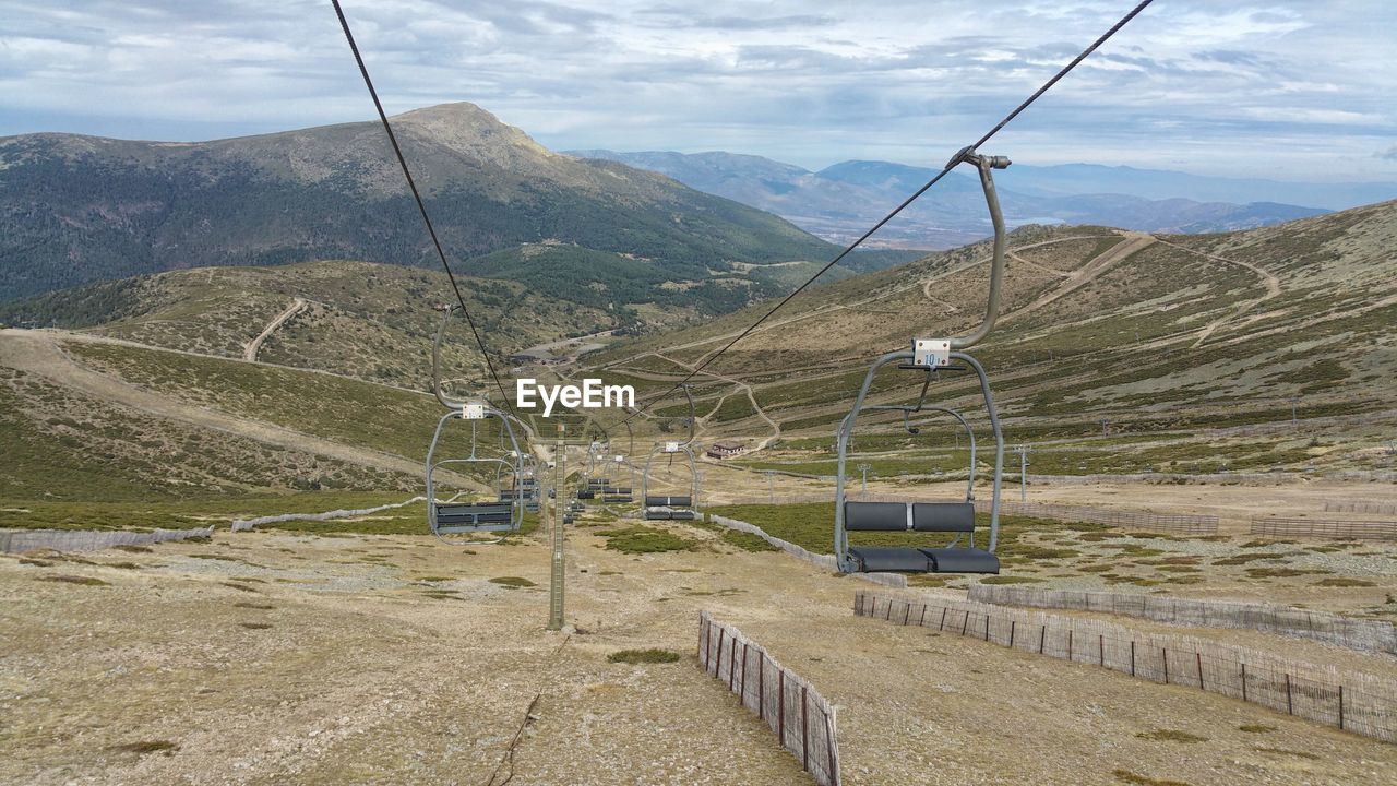 Overhead cable car in mountains against sky