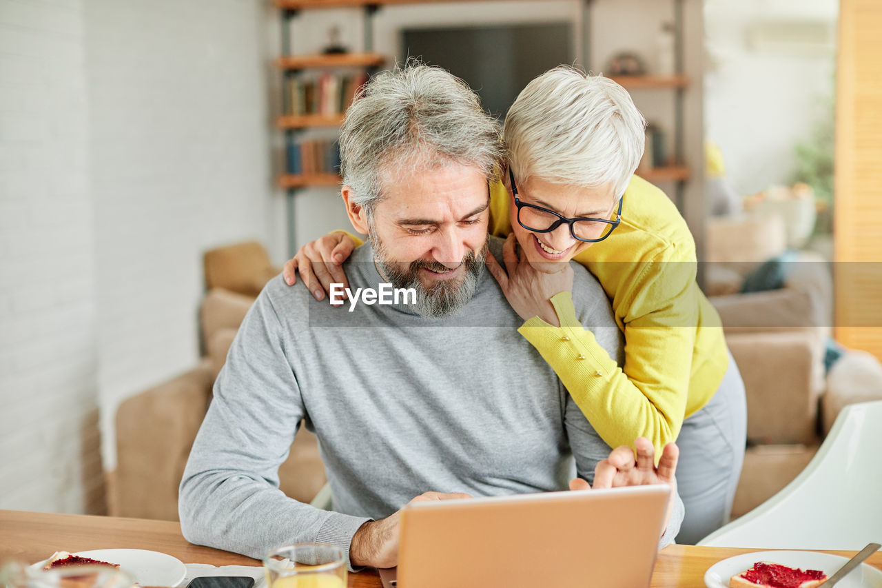 Man and woman using laptop at home