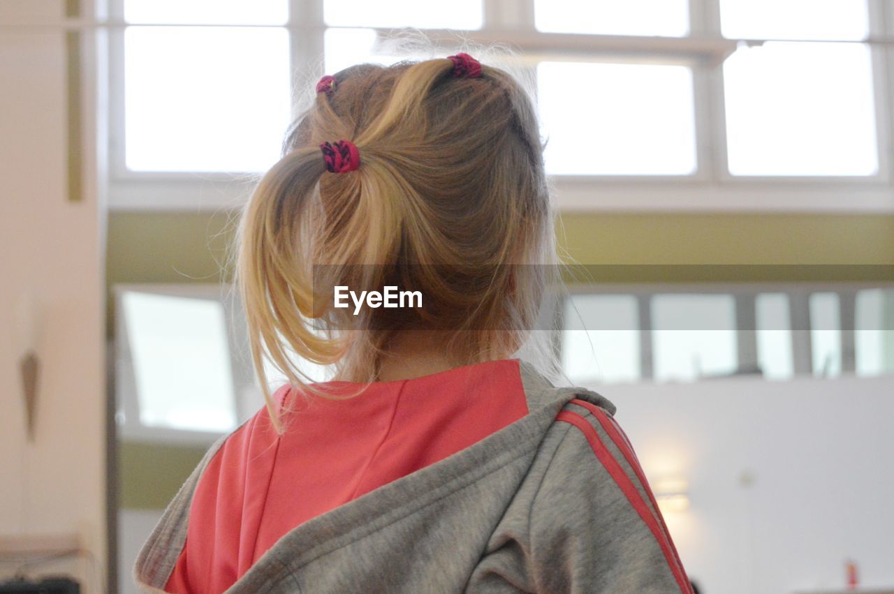 Rear view of girl standing against window