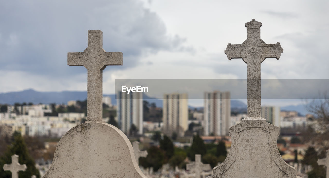 Cross in cemetery against sky