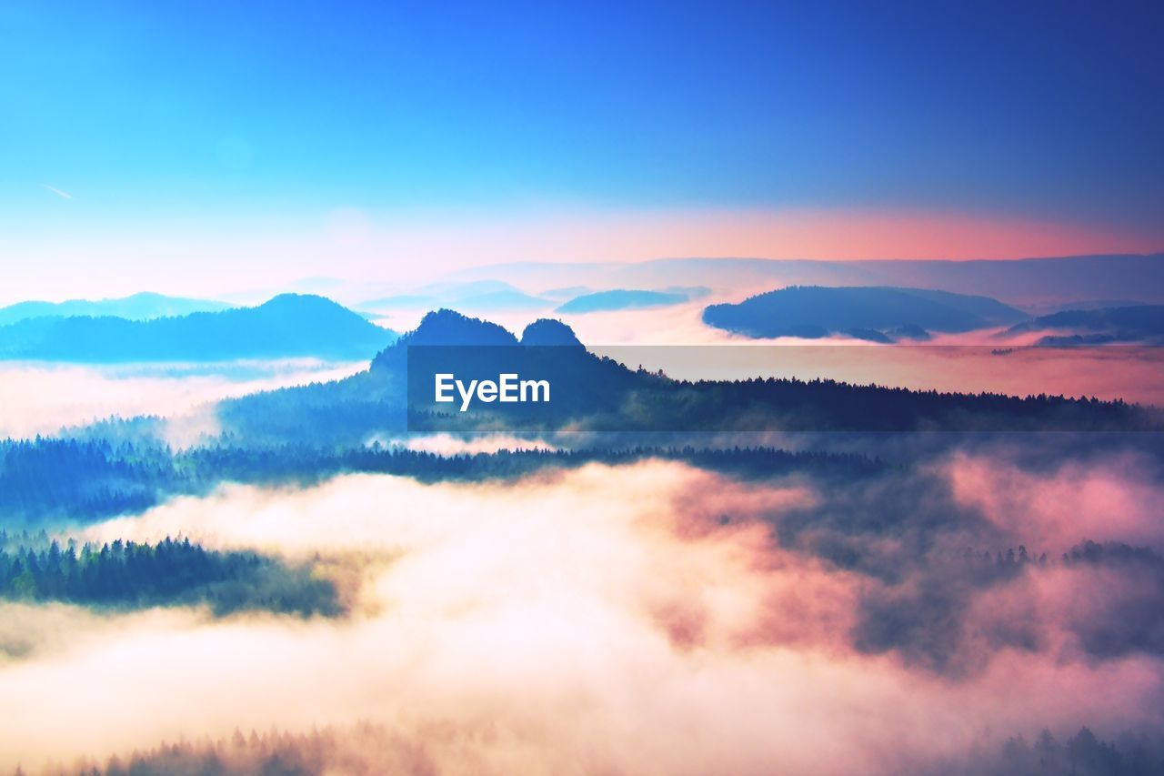 Sunset above misty hilly landscape. fall season fog colored to pink shadows. dreamy view