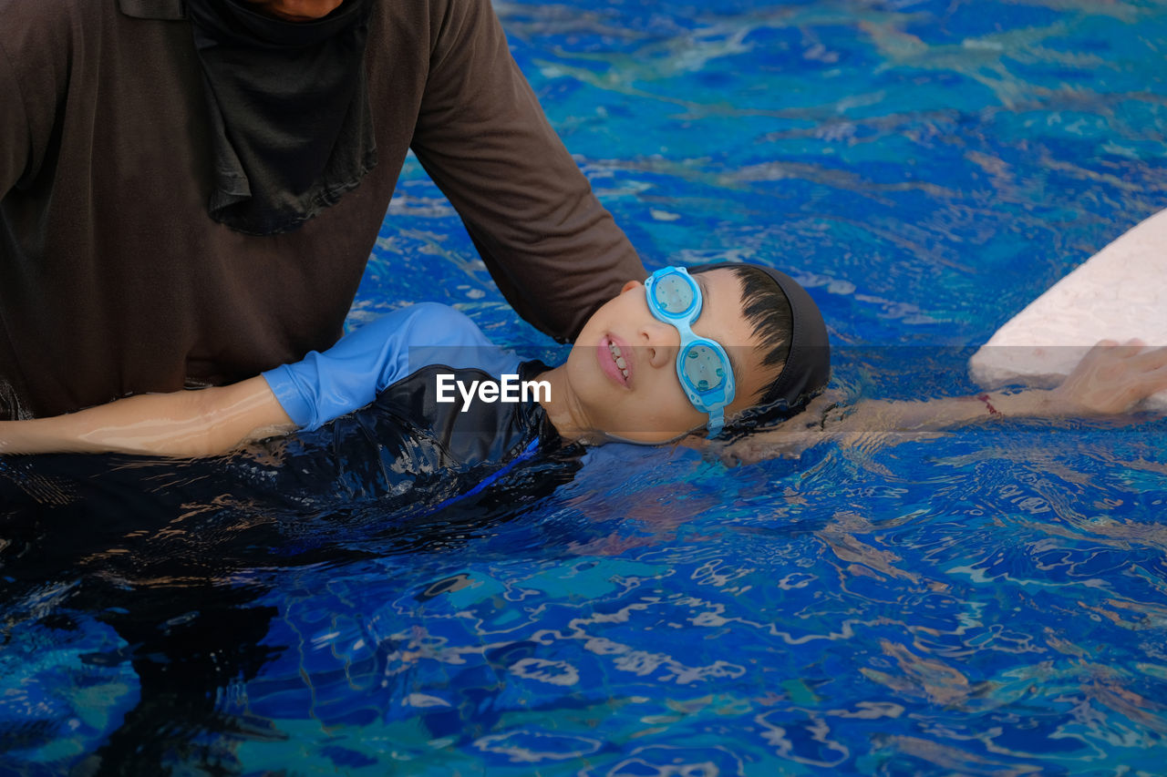 HIGH ANGLE VIEW OF MEN SWIMMING IN POOL