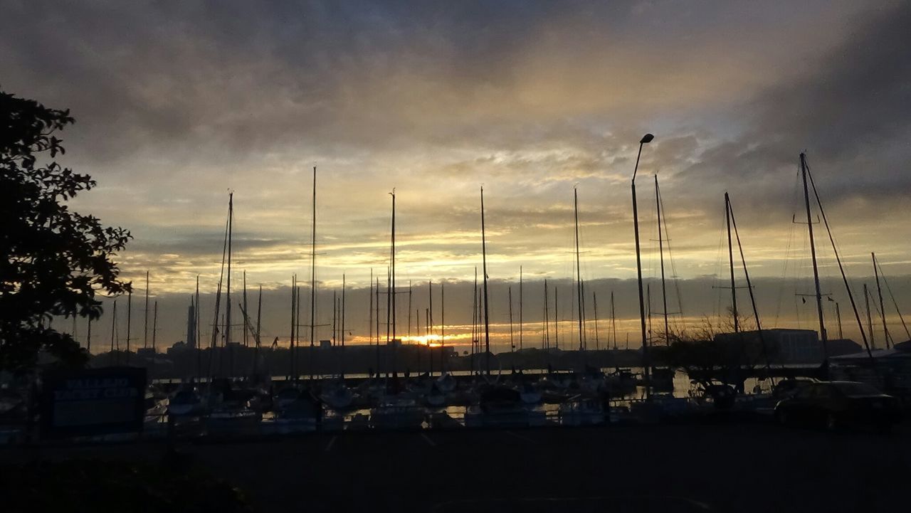 BOATS MOORED AT HARBOR AGAINST CLOUDY SKY