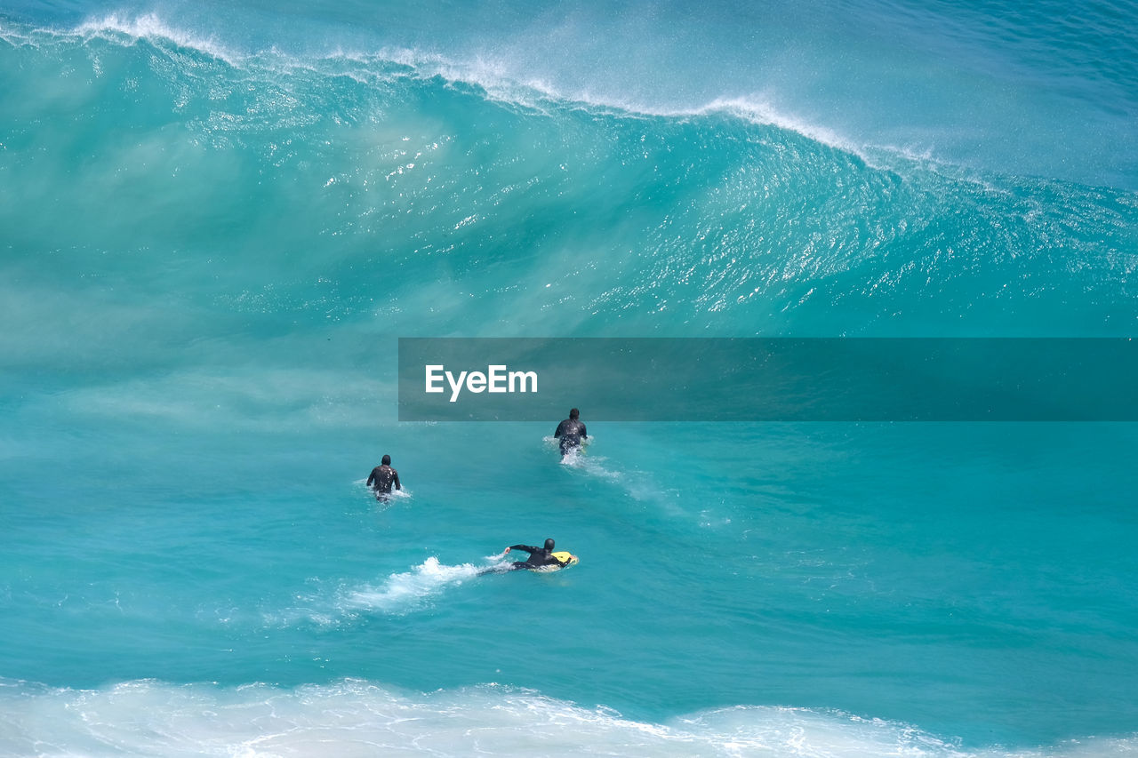 High angle view of people surfing on waves in sea