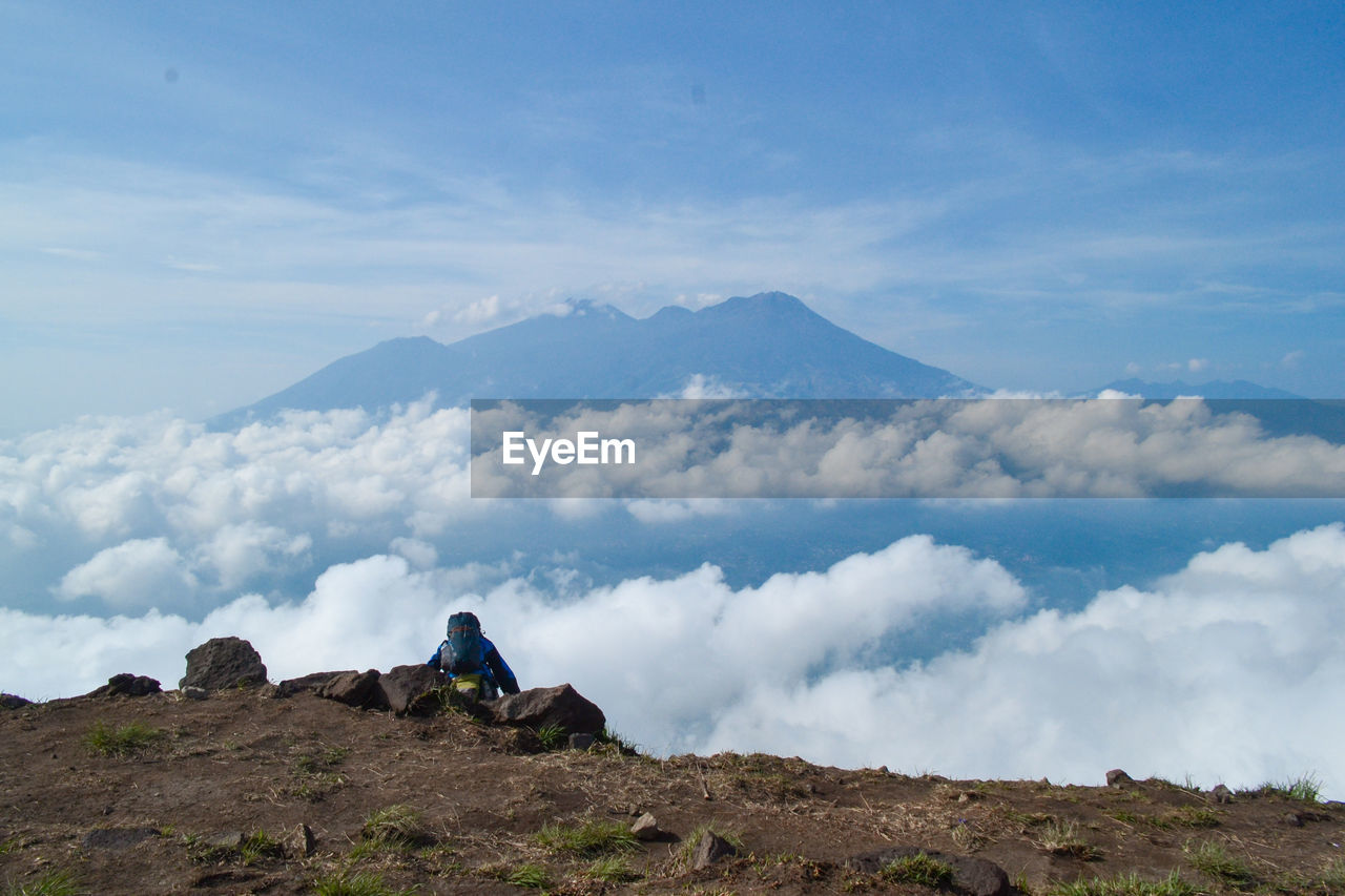 Rear view of hiker on mountain peak against sky