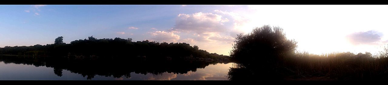 REFLECTION OF TREES IN WATER AT SUNSET