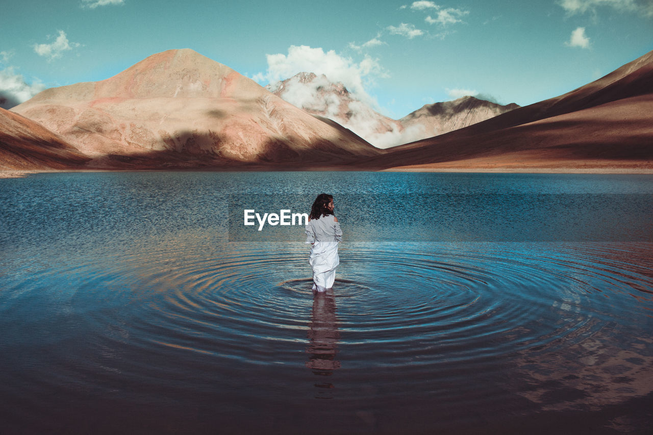 Woman standing in lake against sky