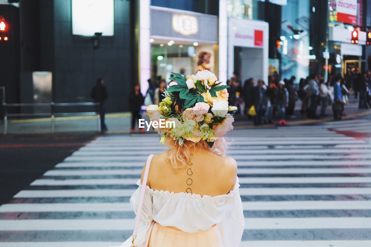 Rear view of a woman with flowers on head crossing road