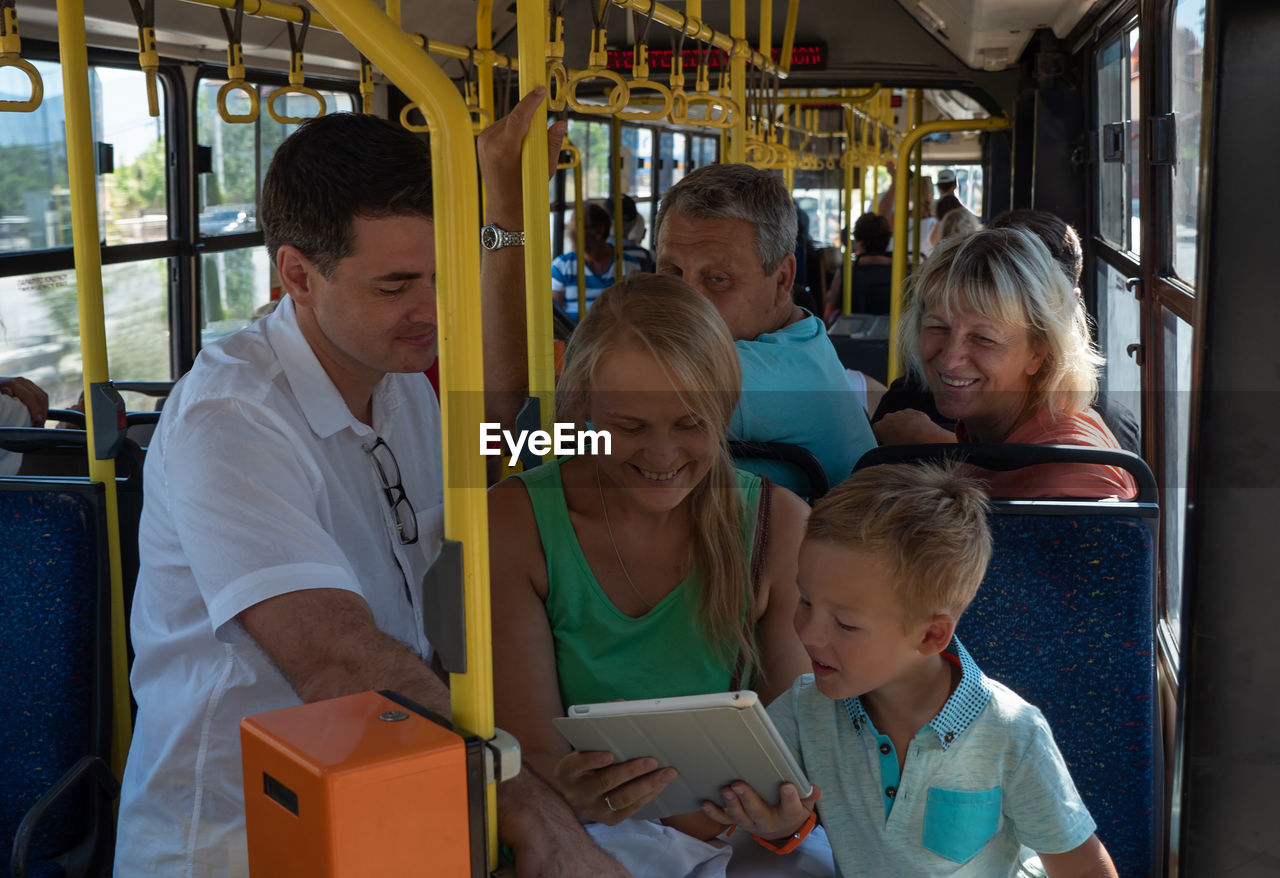 Happy family looking at digital tablet while traveling in bus