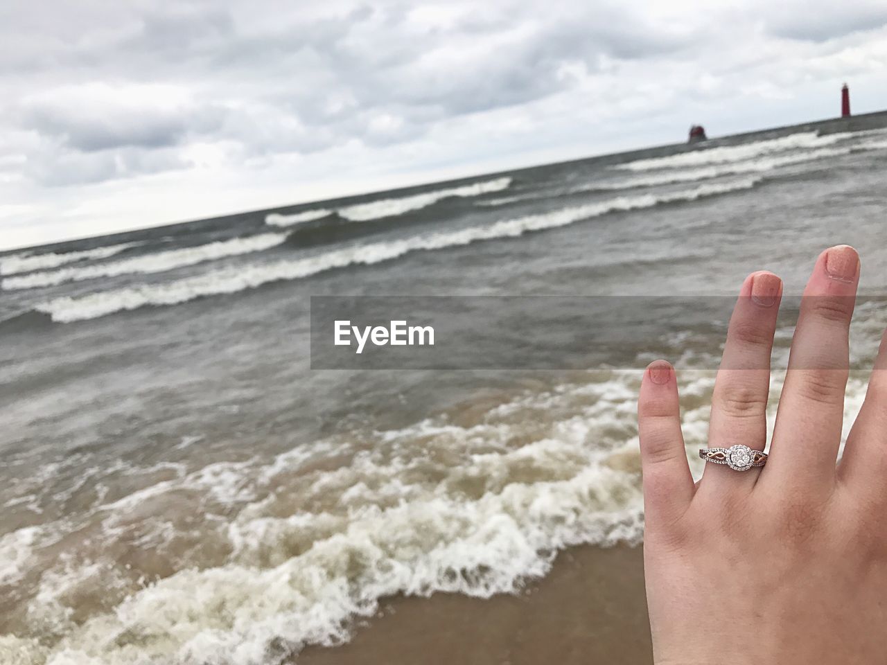 CLOSE-UP OF HAND ON SEA SHORE