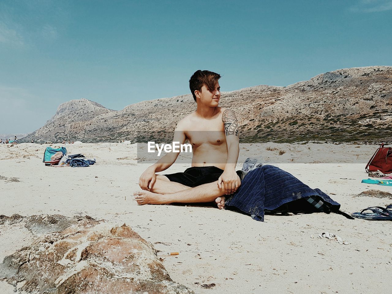 Shirtless boy sitting at beach