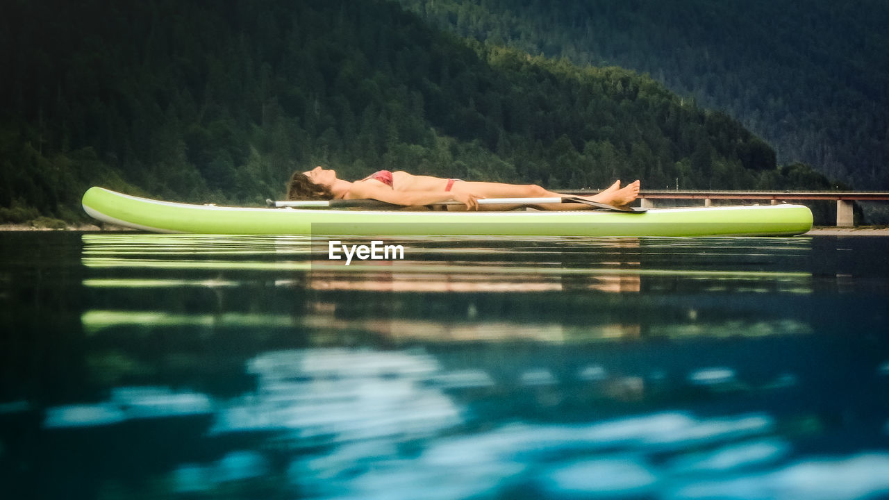 HIGH ANGLE VIEW OF WOMAN RELAXING BY SWIMMING POOL